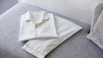 A neatly folded white shirt with gold trim on a gray sofa.