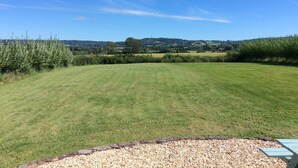 A grassy field with a clear sky, a hedge, and distant hills. - Large Detached "upside Down" Barn, dog friendly with 1 acre enclosed paddock. (wellington)