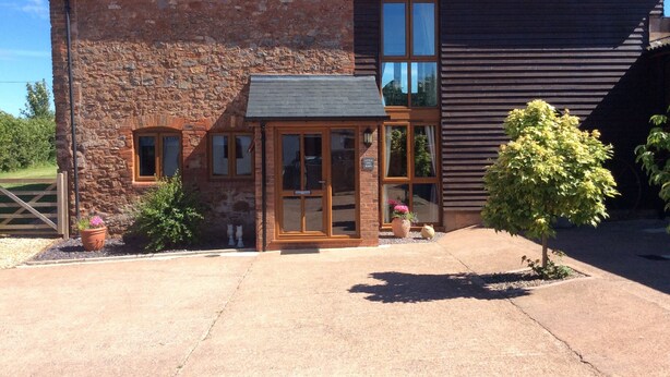 A rustic stone building with a wooden entrance, a small garden, and a sign indicating it is a 'Little Barn'. - Large Detached "upside Down" Barn, dog friendly with 1 acre enclosed paddock. (wellington)