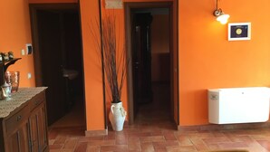Une pièce aux murs orange, avec un meuble en bois, un radiateur blanc et un vase décoré de branches.