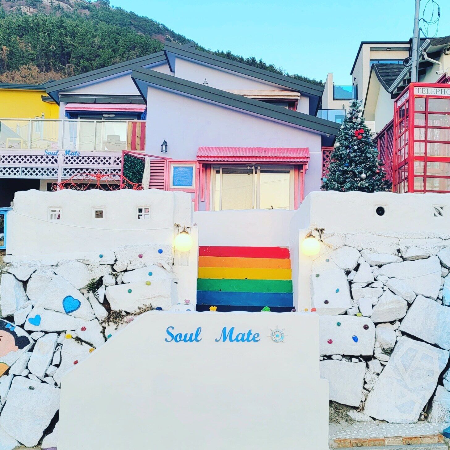 A building with a rainbow-colored door, a sign reading "Soul Mate," and a Christmas tree.