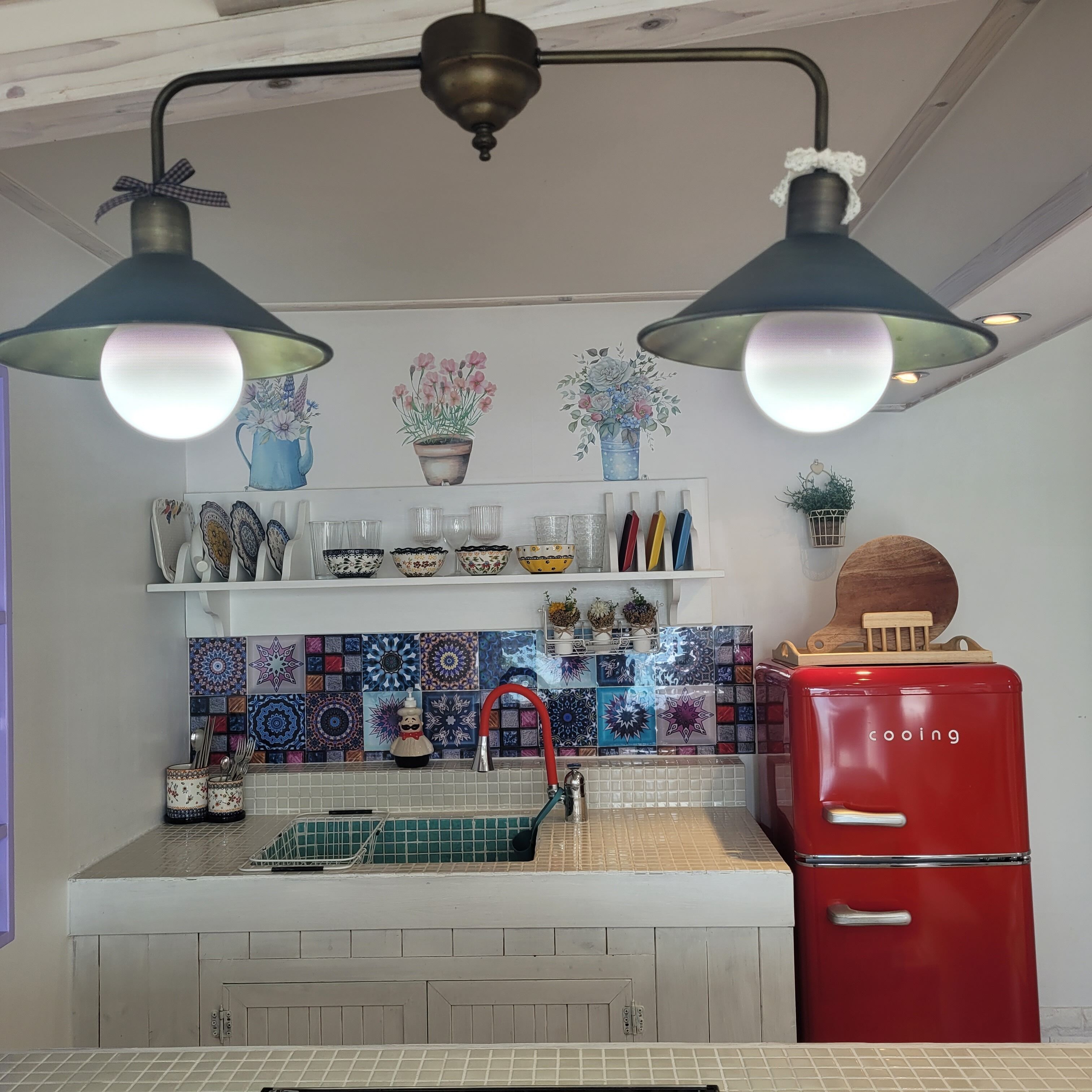 A kitchen with a red refrigerator, a white countertop, and a tiled backsplash.