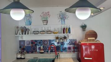 Uma cozinha com geladeira vermelha, bancada branca e painel de azulejos.