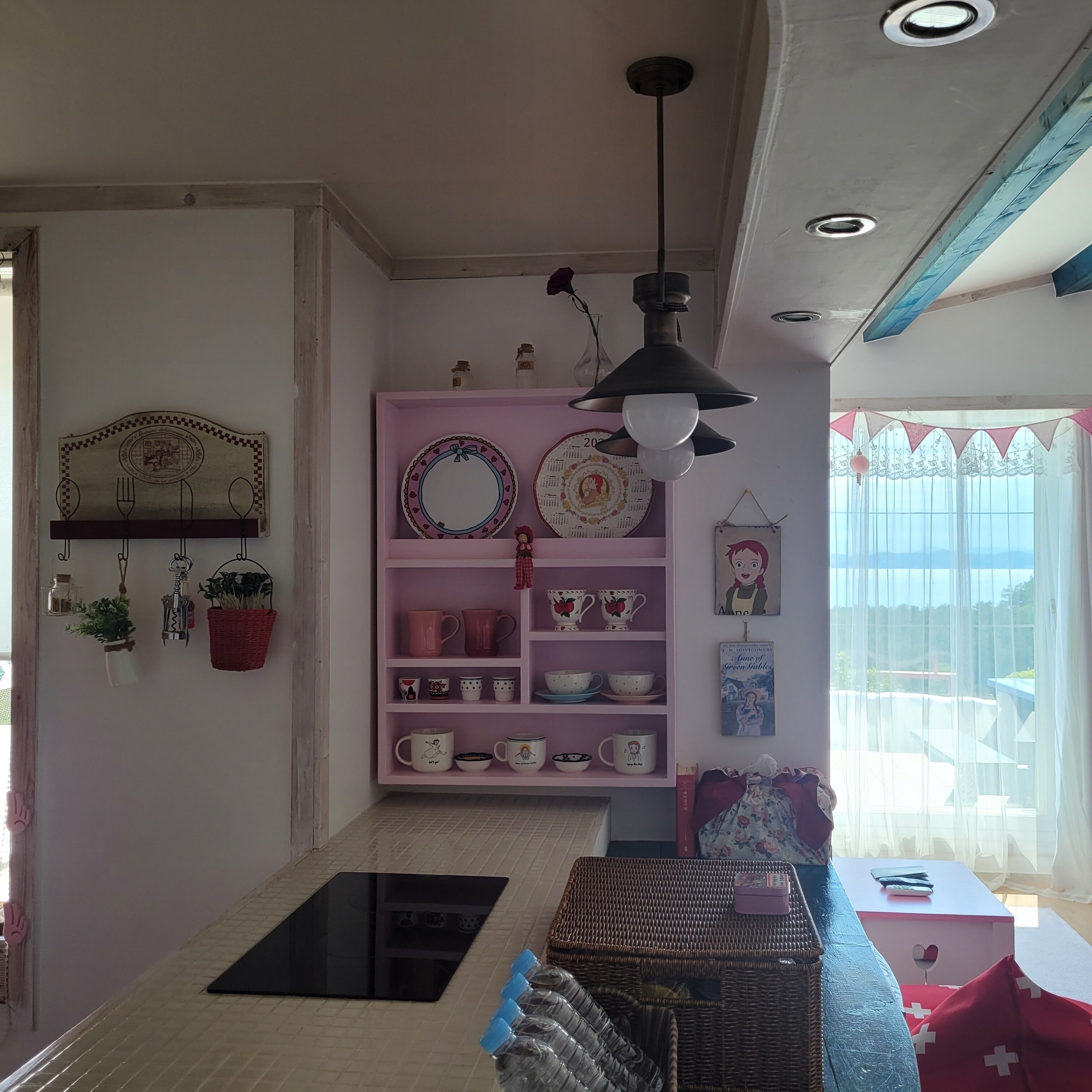 Una habitación con un estante rosa que exhibe diferentes vajillas y una encimera negra.