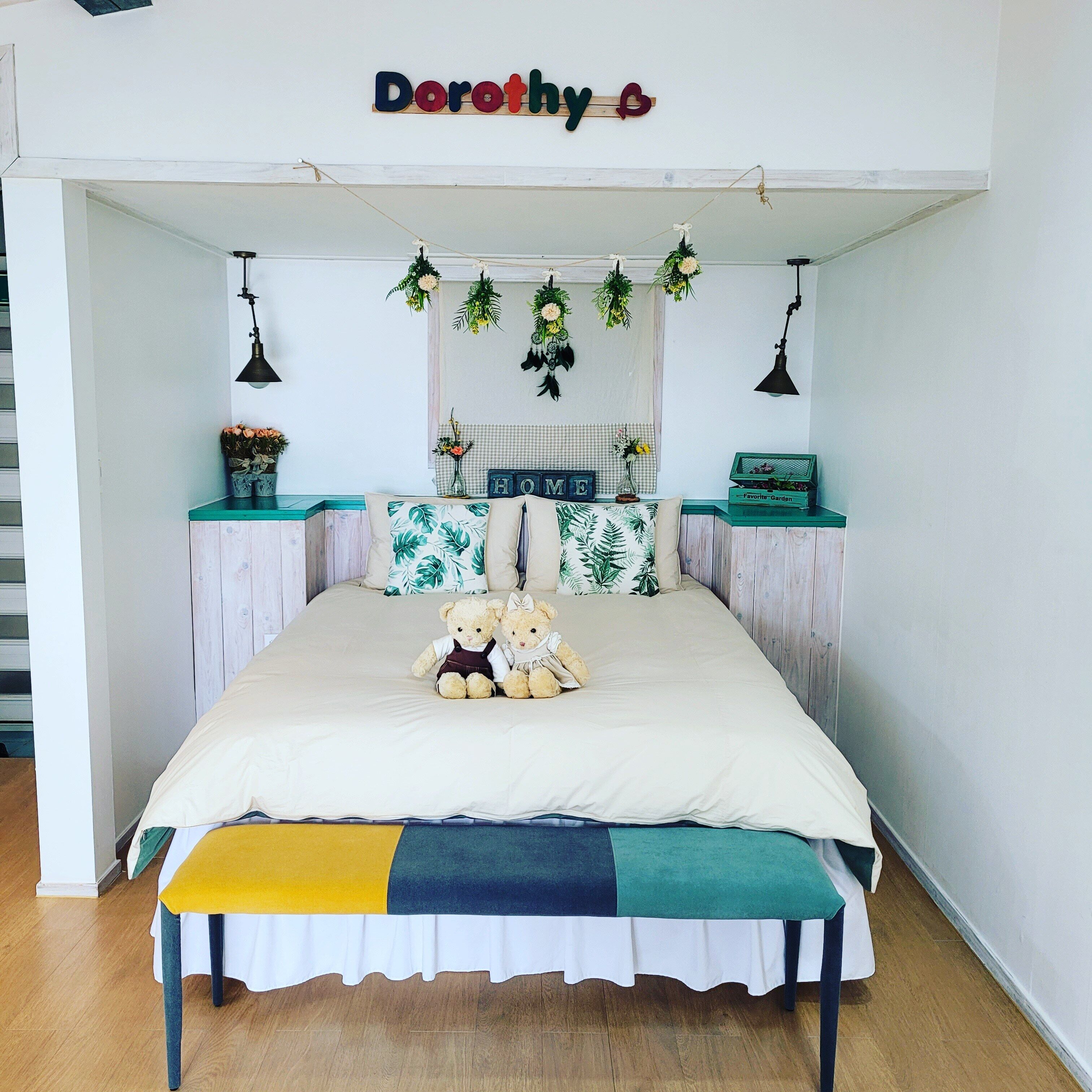 Un dormitorio con una cama, dos osos de peluche, un cartel con un nombre y una caja de jardín con 'Favoritos'.