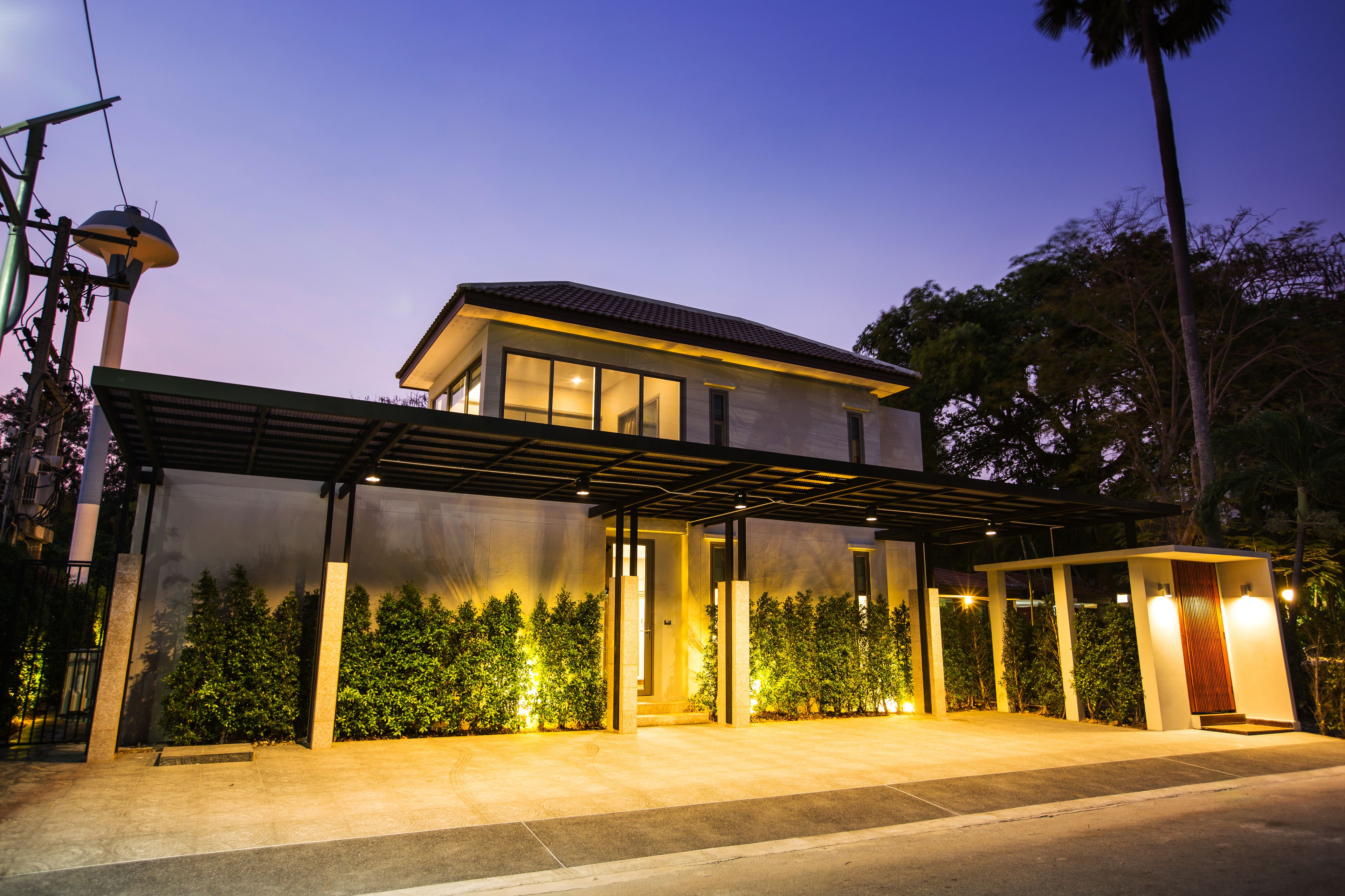 A modern two-story house with a covered patio, large windows, and a well-lit entrance.