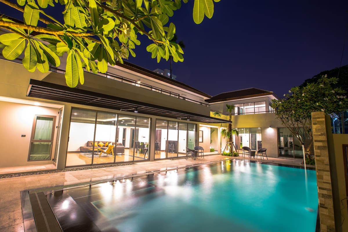 A modern house with a swimming pool, large glass doors, and outdoor furniture.