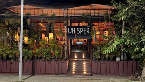 A building with a sign reading 'WHISPER' and a staircase leading to the entrance.