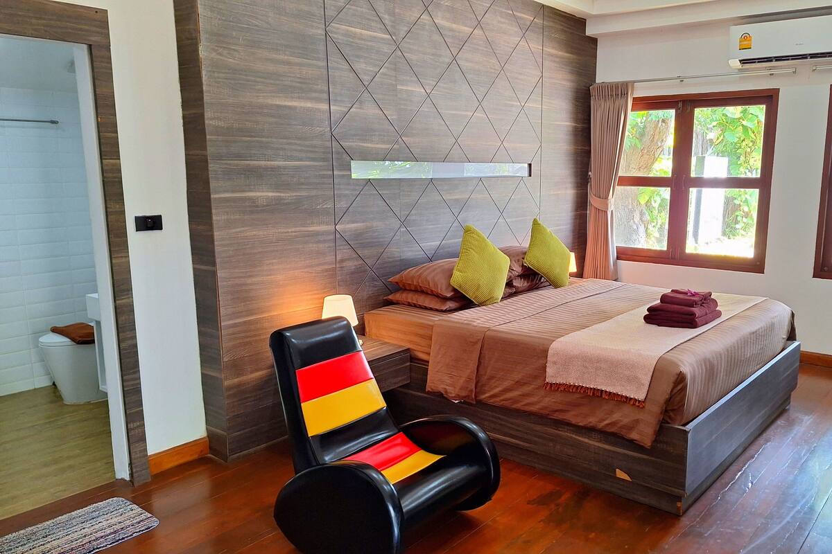A modern bedroom with a bed, a chair, and a window.
