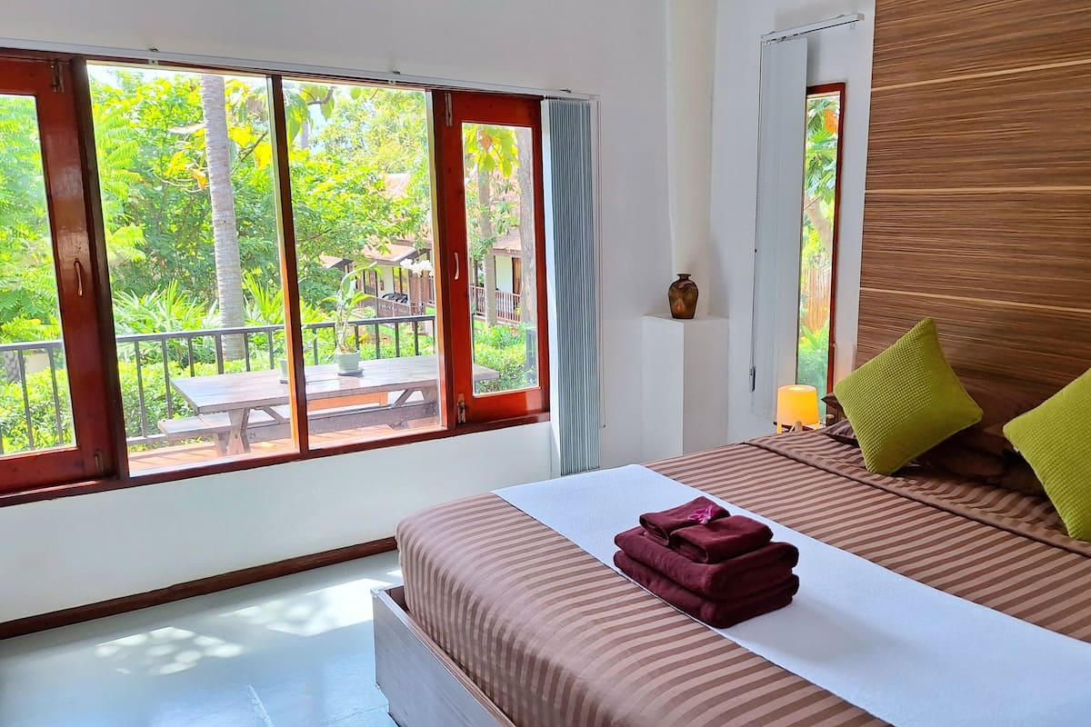 A bedroom with a bed, a window, and a view of the outdoors.