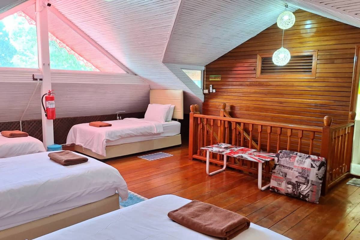 A cozy room with two beds, a small table, and a wooden bench.