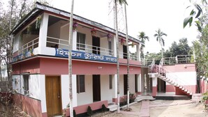 A two-story building with a balcony, a staircase, and a sign in a foreign language.