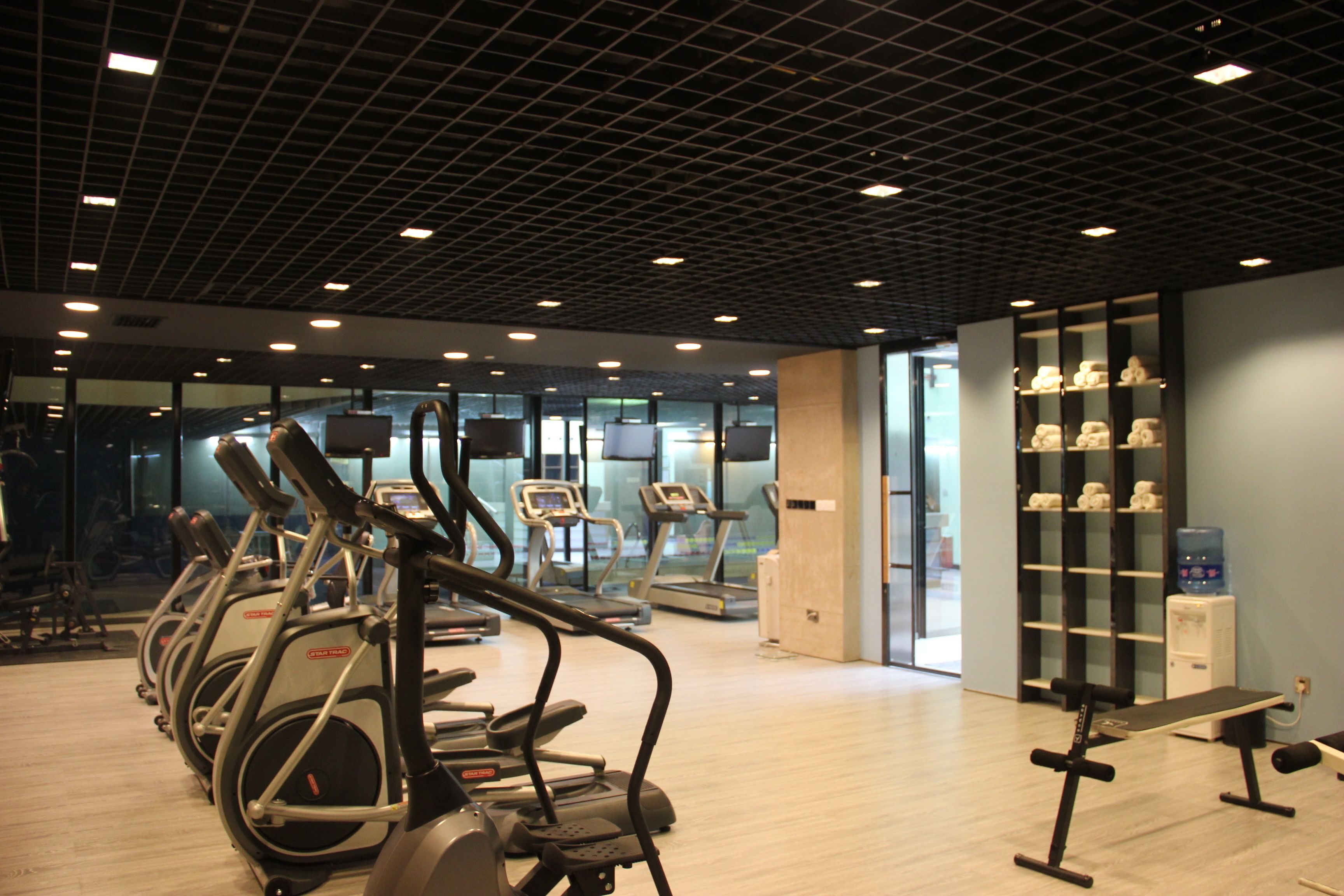 Un gimnasio con cintas de correr, elípticas y un dispensador de agua.