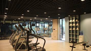 Un gimnasio con cintas de correr, elípticas y un dispensador de agua.