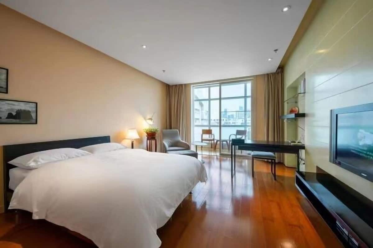 Hotelkamer met een groot bed, een bureau, een stoel, een televisie en uitzicht op de stad.