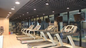 A gym with treadmills, exercise machines, and large windows. - GreenPark Hotel Tianjin (Tianjin)