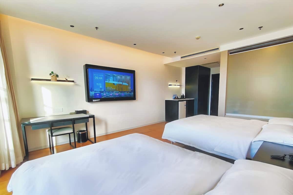 Een hotelkamer met twee bedden, een bureau, een televisie en een minibar.