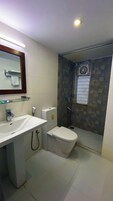 Un baño moderno con cabina de ducha de vidrio, un lavabo blanco y un inodoro.