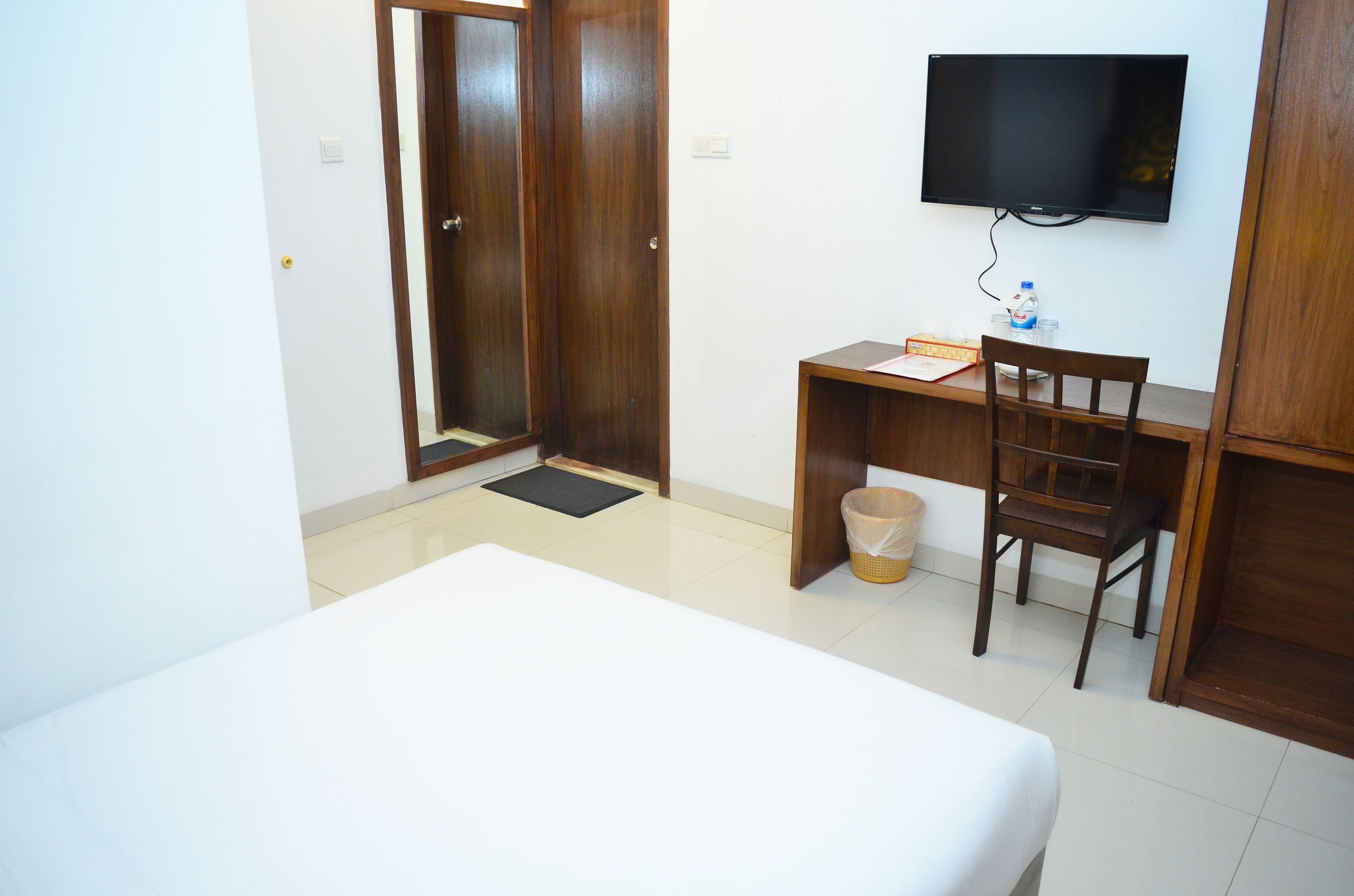 Ein Hotelzimmer mit Bett, Schreibtisch, Stuhl, Fernseher und Kleiderschrank.