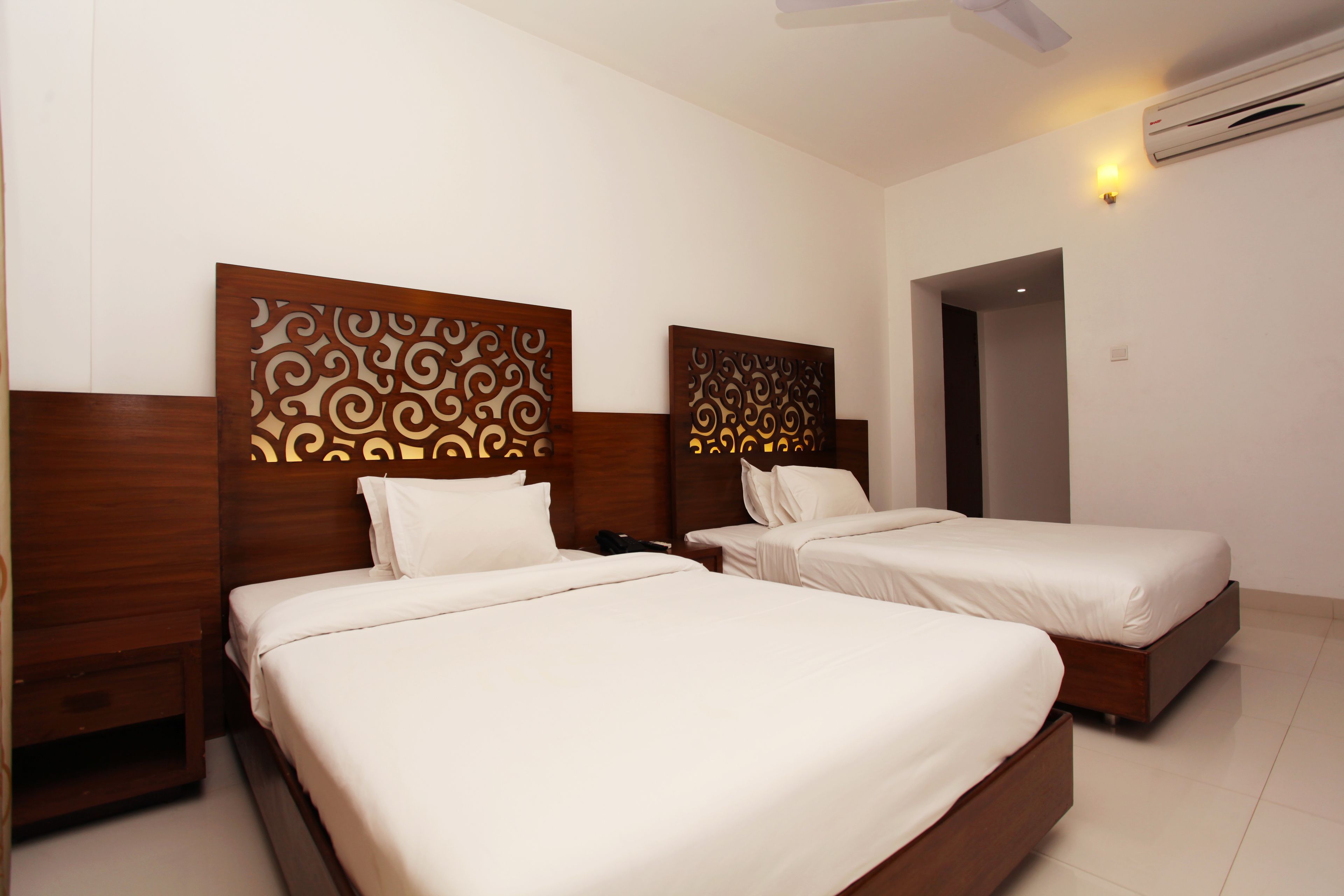 Ein Hotelzimmer mit zwei Betten, Holz-Kopfteilen und modernem Design.