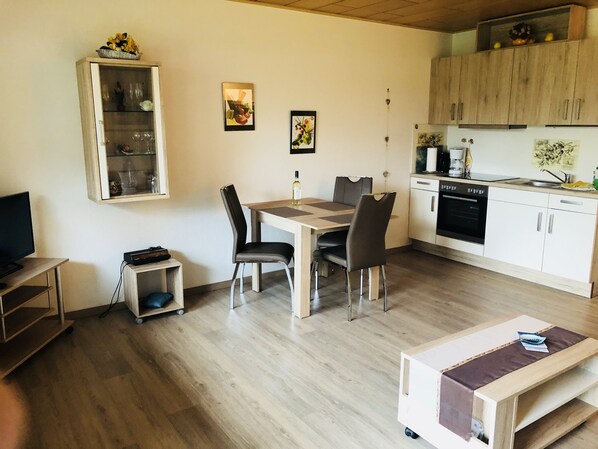 Un espace de vie compact comprenant un coin repas, une kitchenette et un téléviseur.