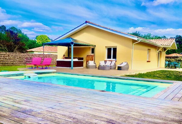 A house with a swimming pool, outdoor seating, and a covered patio.