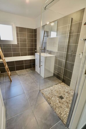 A bathroom with a shower, a sink, and a mirror.