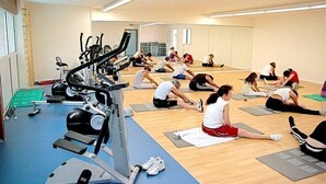 Un gimnasio con diverso equipo de ejercicio y personas realizando estiramientos.