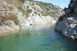 A clear, calm river with rocky banks and sparse vegetation.