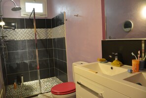 A bathroom with a shower, toilet, sink, and a mirror.