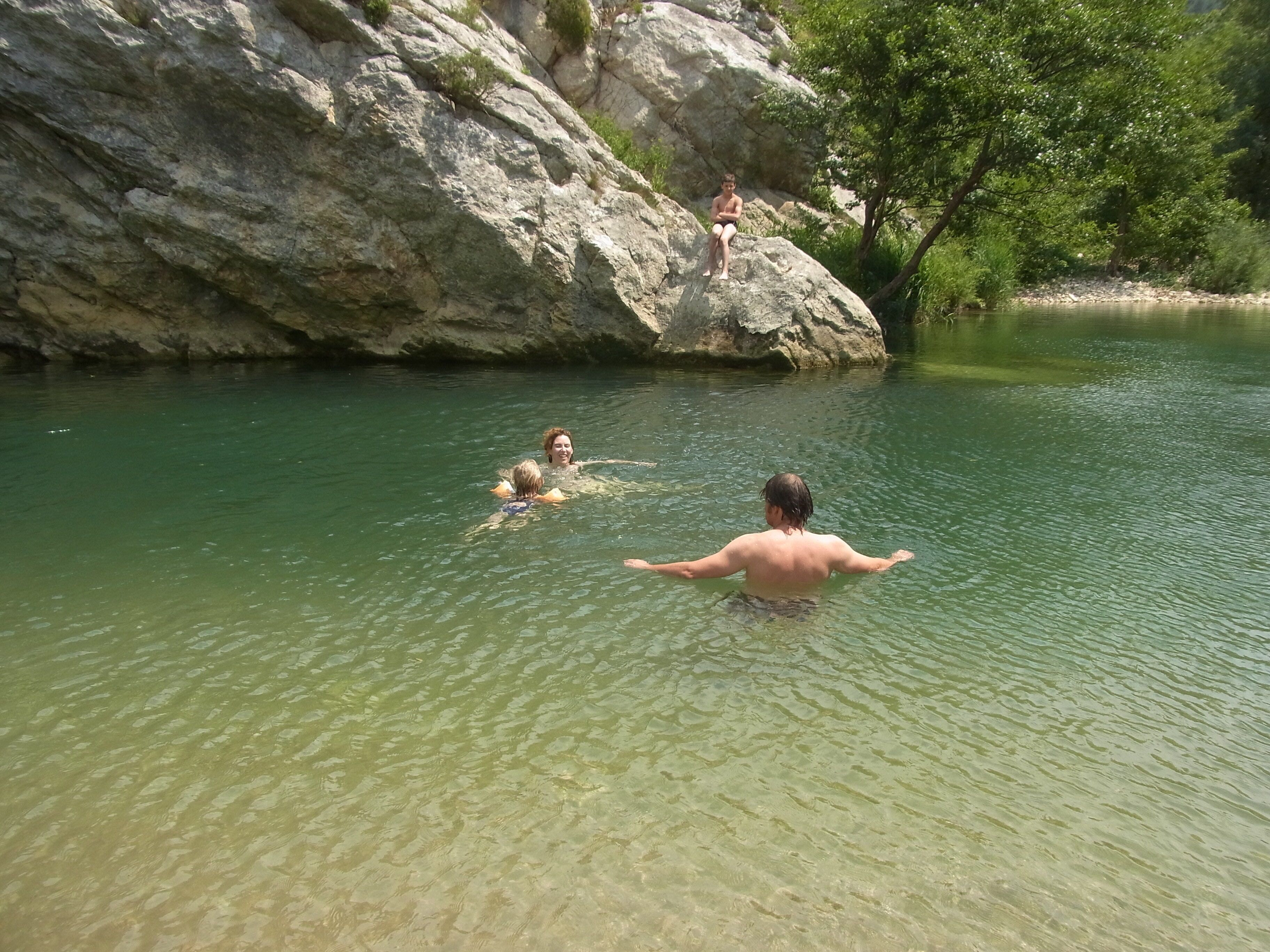 A natural outdoor setting with clear water, rocky terrain, and trees.