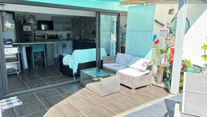 A modern kitchen with a dining area, a glass door leading to a balcony with a sofa and a coffee table. - Atypical 2 bedroom ground floor apartment with private pool  (saint pierre)