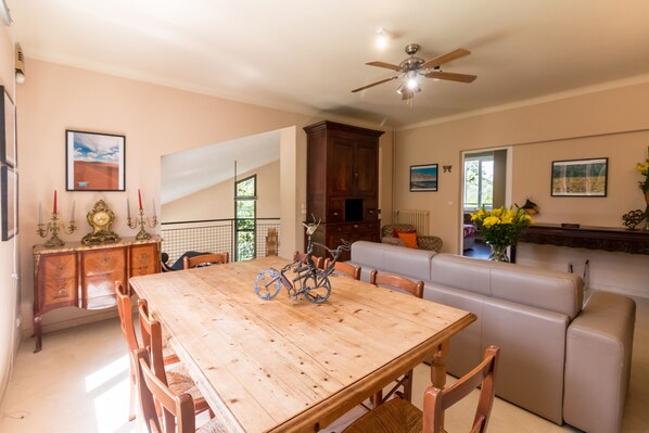 A dining area with a wooden table and chairs, a ceiling fan, and a sofa. - "VILLA TSAVORITE - CANNES CALIFORNIE" : large swimming pool, 4 bedrooms & 210 m2. (Cannes)