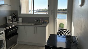 Eine kleine Küche mit Meerblick, ein Essbereich mit einem schwarzen Tisch und eine Waschmaschine.
