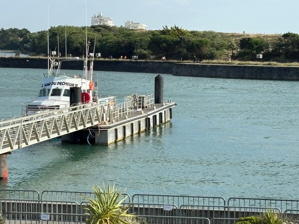 A boat docked at a pier with a metal railing and a sign that reads "L'AMI DU PECHEUR".