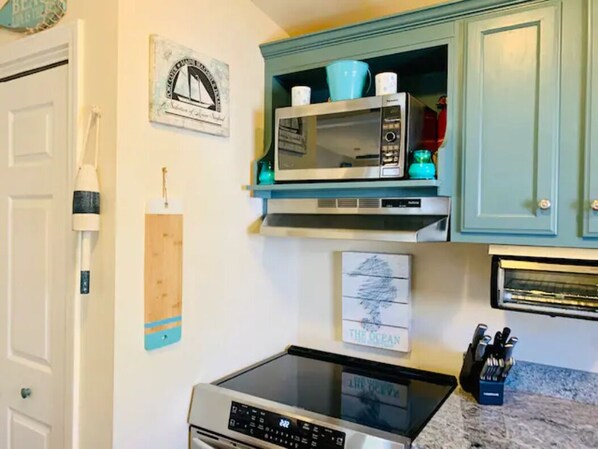 Una cocina con microondas, tostadora y cafetera sobre la encimera.