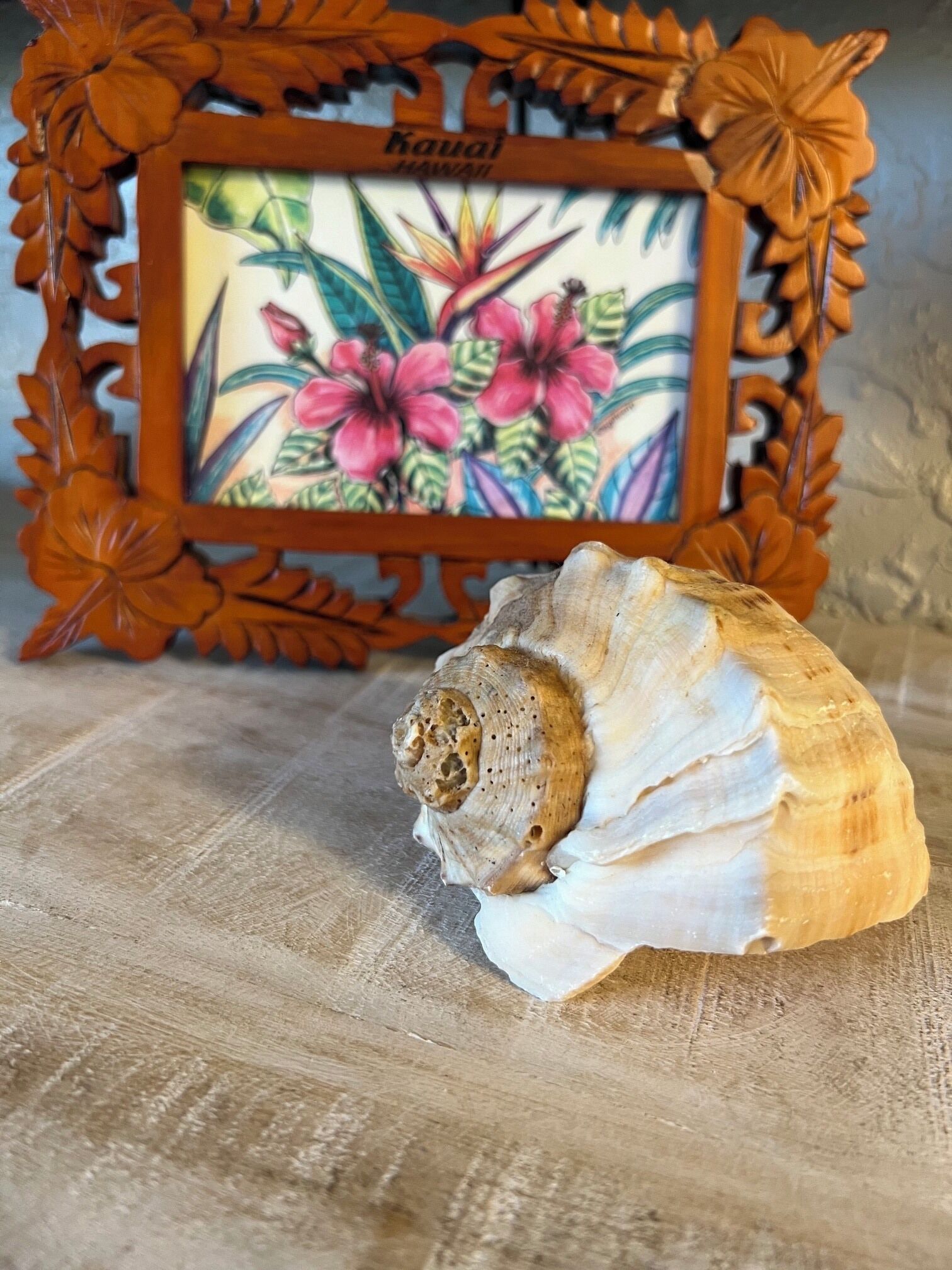 Een houten lijst met een bloemistisch ontwerp en de tekst 'Kauai Hawaii'.