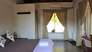 A bedroom with a bed, a bedside table, a chair, a window with curtains, and a wall-mounted air conditioner. - e-stay Hanthana Kandy (Kandy)