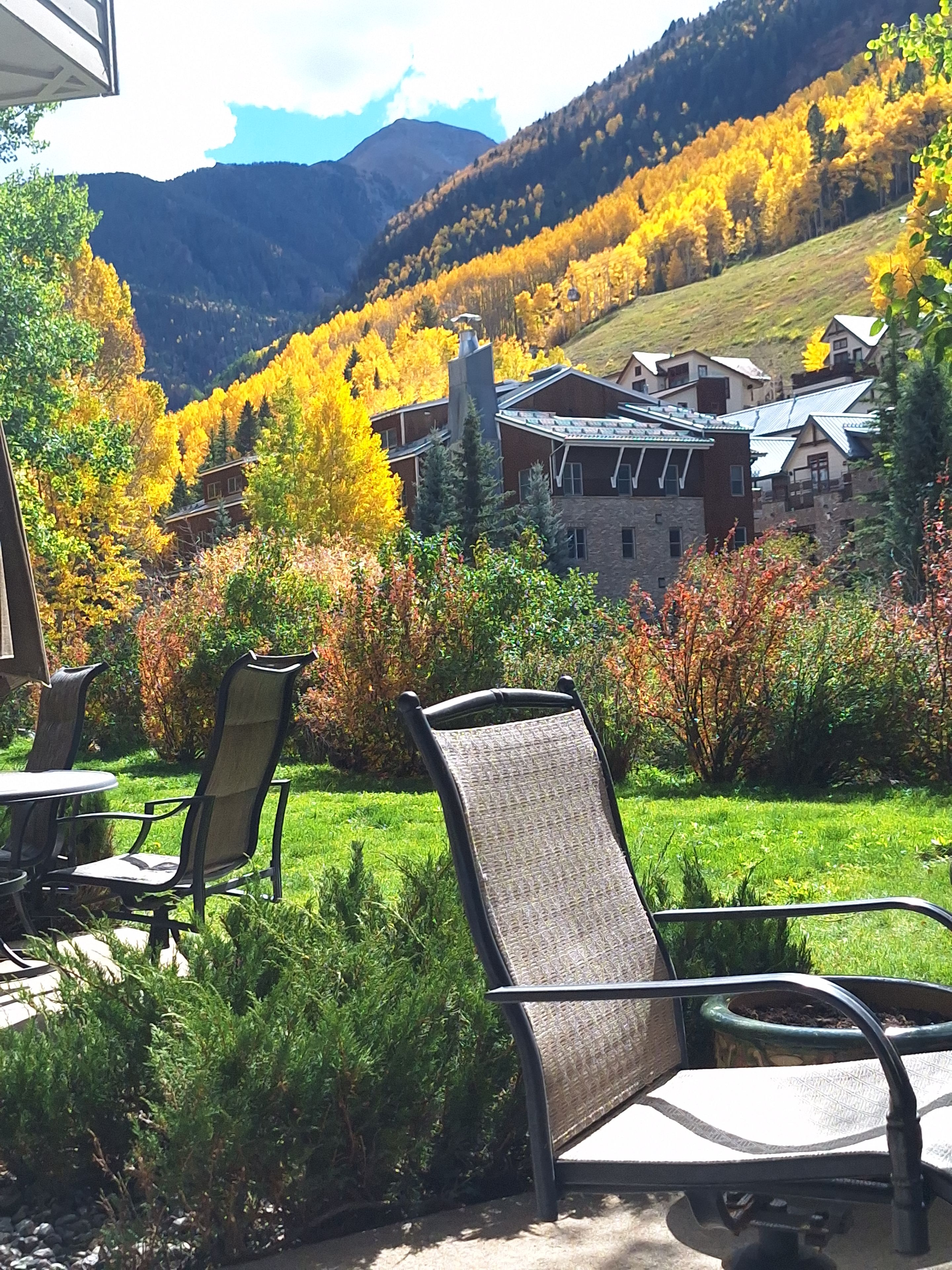 A patio area with outdoor furniture, a view of a mountain range, and autumn-colored trees.