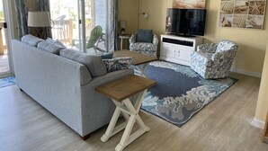 A living room with a sofa, a coffee table, a TV, and a patterned rug. - LAST MIN DISCOUNT LABOR DAY! 2nd ROW EASY beach access 1/2 block Ocean View (Emerald Isle)