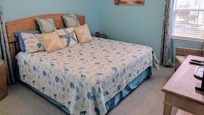 A bedroom with a bed, a nightstand, a wicker chair, and a window with curtains. - LAST MIN DISCOUNT LABOR DAY! 2nd ROW EASY beach access 1/2 block Ocean View (Emerald Isle)