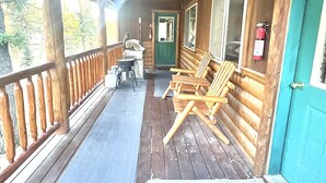 A covered porch with wooden railings, a grill, and several wooden chairs. - Rhodehouse Retreat! Your destination for Year Round Fun! (Island Park)