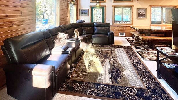 A cozy living room with a sectional sofa, a fireplace, and mounted animal heads on the wall. - Rhodehouse Retreat! Your destination for Year Round Fun! (Island Park)