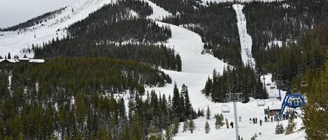 Un paisaje montañoso nevado con un telesilla y un edificio en primer plano.