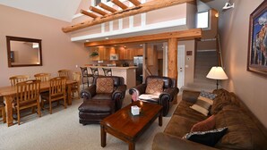 A spacious living area with a dining table, leather sofas, and a kitchen in the background. - Casa Moonlight Two - Ideal Rental for Summer Activities and Trips to Yellowstone (Big Sky)