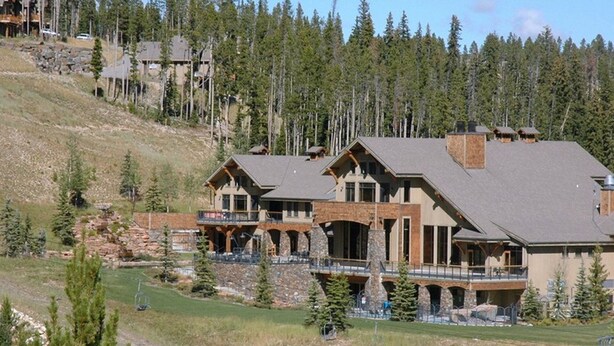 A large, multi-story lodge with a stone facade, multiple balconies, and a ski lift visible in the background. - Casa Moonlight Two - Ideal Rental for Summer Activities and Trips to Yellowstone (Big Sky)