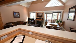 A cozy living room with a fireplace, a television, and a dining area with wooden chairs and a table. - Casa Moonlight Two - Ideal Rental for Summer Activities and Trips to Yellowstone (Big Sky)