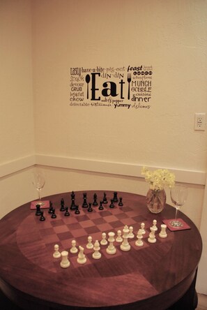 A chessboard with pieces set up for a game, a vase with flowers, and a wall with a word cloud related to food and dining. - Waterfront Historic Bungalow One• Ferry to SF (Vallejo)