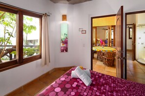 A bedroom with a bed, a window, and a view of a dining area.