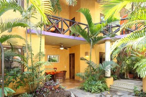A courtyard with a dining area, potted plants, and a staircase.